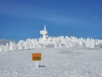 Winter scene at Hakkoda, Japan, showcasing a serene snowy landscape. Skiers descend a mountain slope in a popular ski resort, highlighting the allure of winter sports in the scenic, snow-laden terrain.