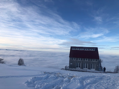 View of Ski centar Cmiljača in Rakita Montenegro featuring a mountain hut amidst a snowy landscape. A vivacious winter sports scene unfolds with skiers descending from the ski resort.
