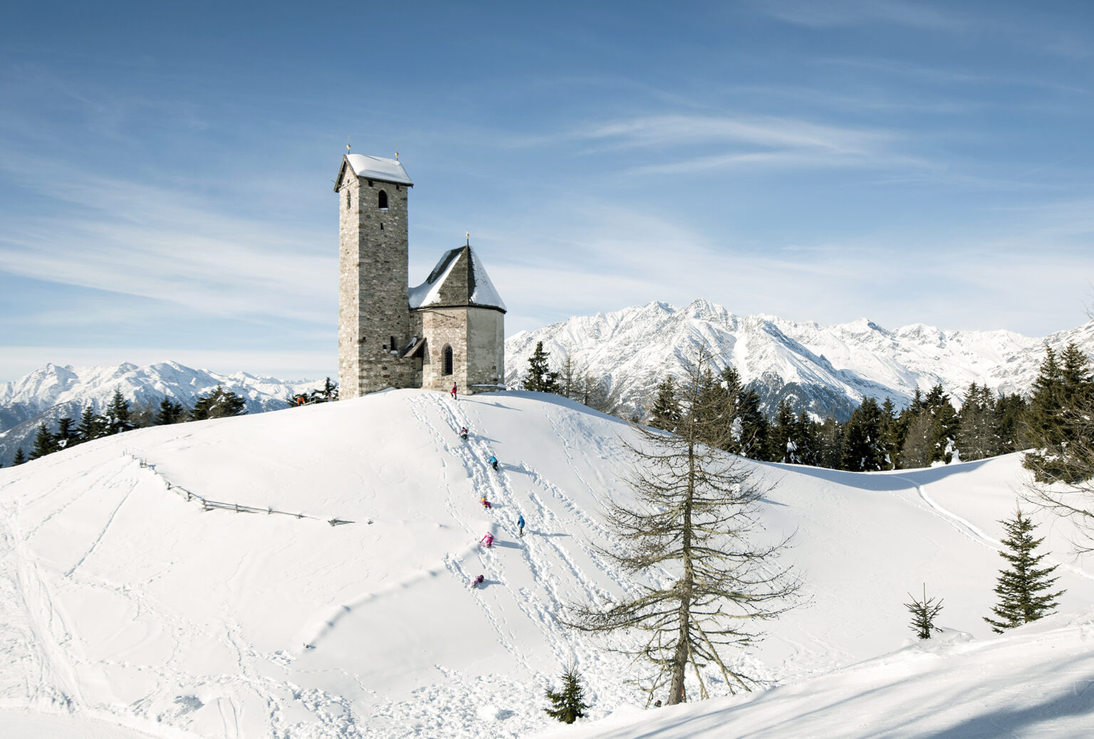 A charming chalet sits amidst a bustling winter sports scene at the Vigiljoch – Lana ski resort in South Tyrol Italy. Spectacular winter scenery with pristine snow envelops the lively resort.