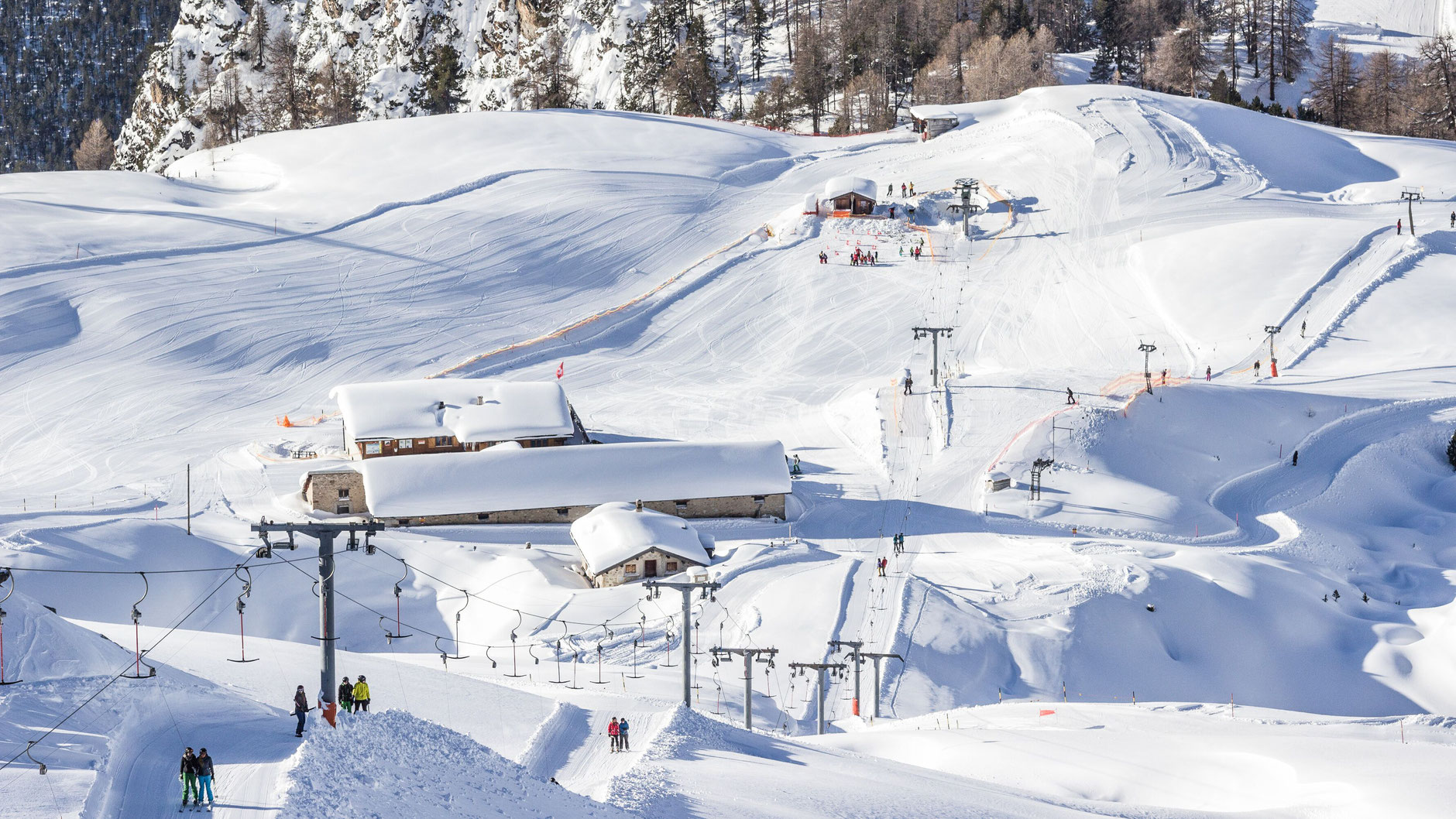 Winter scene at Skigebiet und Minschuns ski resort in Eastern Switzerland, featuring skiers enjoying the snow-covered slopes, with a ski lift visible in the background.