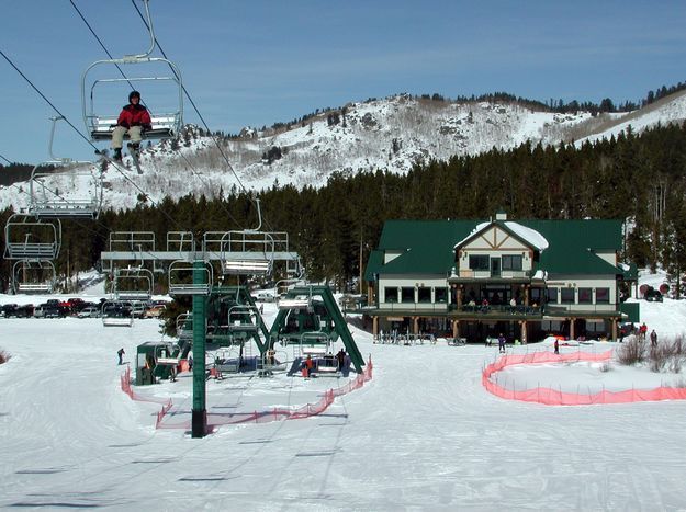 A picturesque winter sports scene at White Pine ski resort in Pinedale Wyoming with a ski lift in the background and a skier ready to descent the snowy hill.