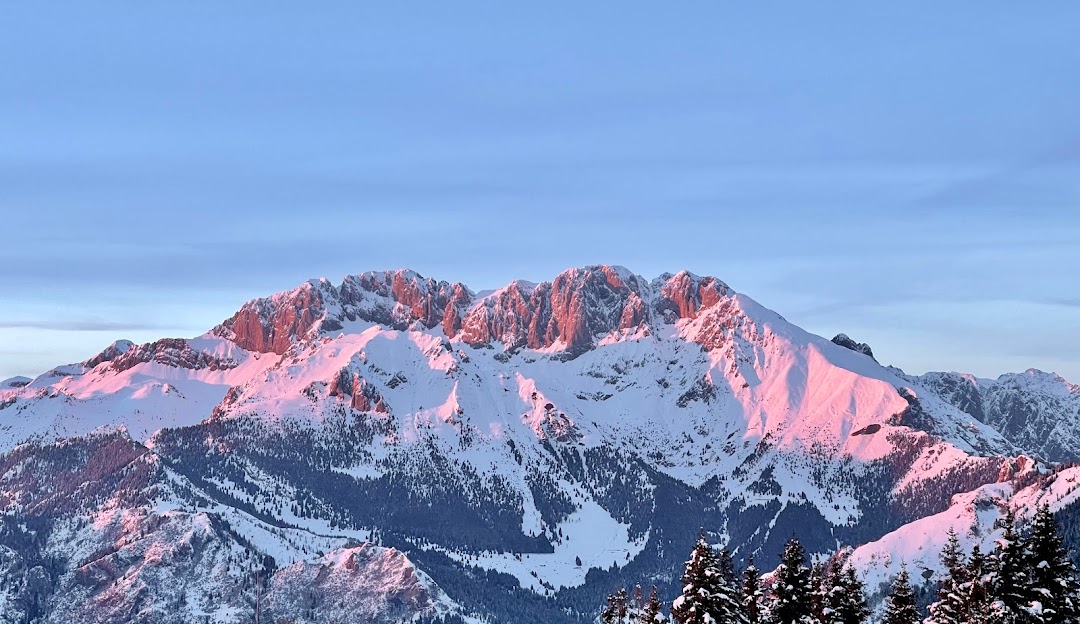 View of the scenic Monte Pora in Lombardy, Italy during winter; featuring a charming challet nestled against the imposing mountain backdrop, and a bustling winter sports scene.