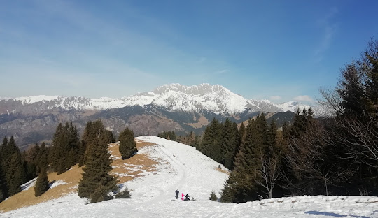 A scenic winter view at Monte Pora ski resort in Lombardy Italy. Image features a charming chalet nestled on the mountainside with skiers enjoying winter sports amidst the picturesque snowy peaks.