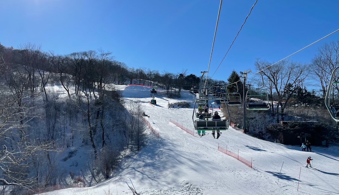 Winter scene in Karuizawa, Japan, featuring a ski lift and skier amidst the stunning winter scenery of a bustling ski resort.