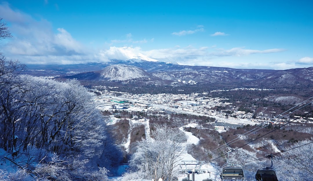Winter scene in Karuizawa, Japan, featuring a gorgeous blanket of snow, ski tracks, a charming chalet by the snowy slope, synonymous with winter sport activities.