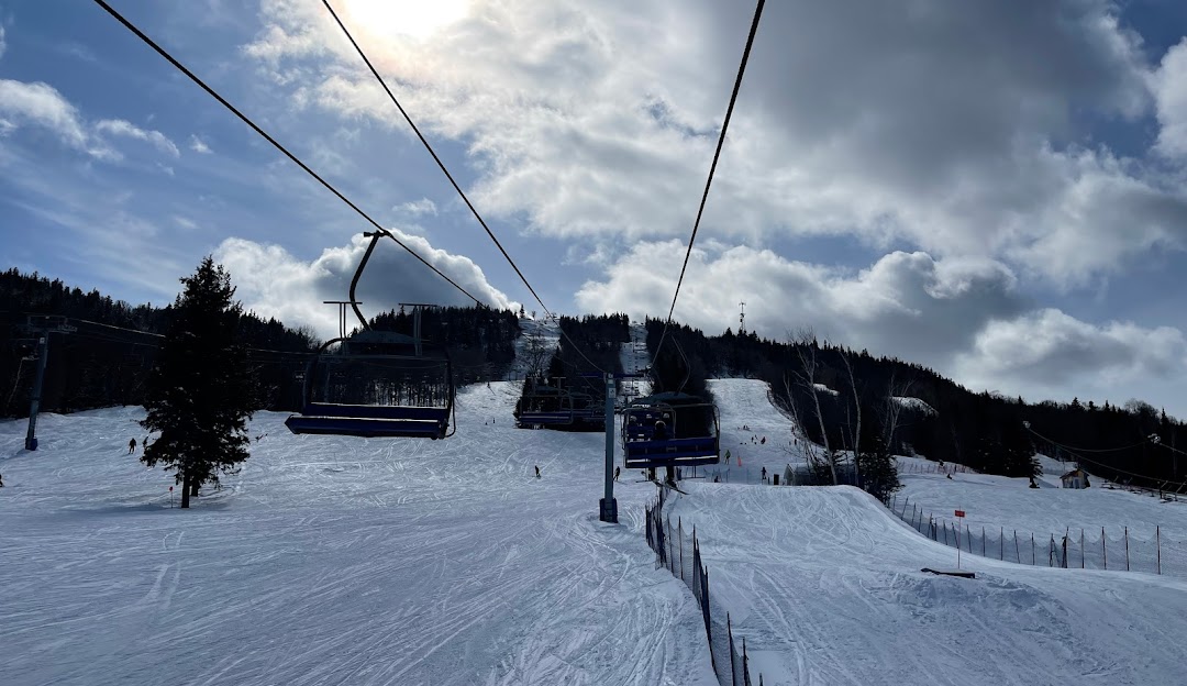 Ski lift ascending at Ski La Réserve in Quebec, Canada with a skier navigating the snow-covered slopes, depicting a lively winter sports scene at the ski resort.