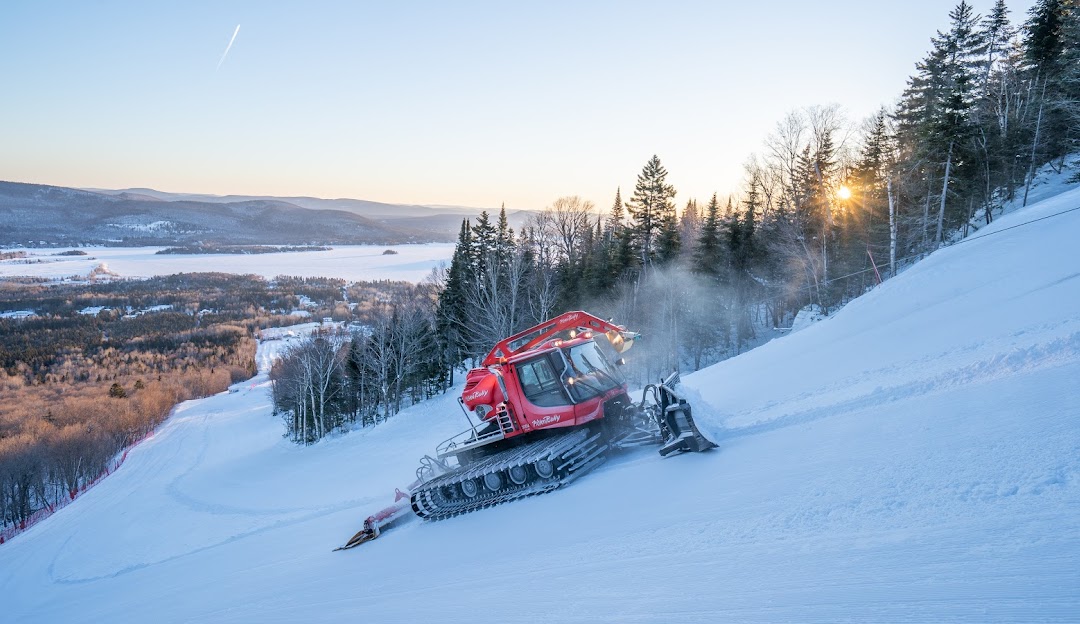 Winter sports enthusiasts enjoying a day at Ski La Réserve in Quebec, Canada, with a snowmobile visible. The stunning beauty of the ski resort, replete with its ski lift, fills the picturesque winter scenery.