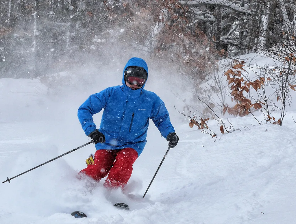 Caberfae Peaks in USA - a man in a blue jacket skiing down a hill.