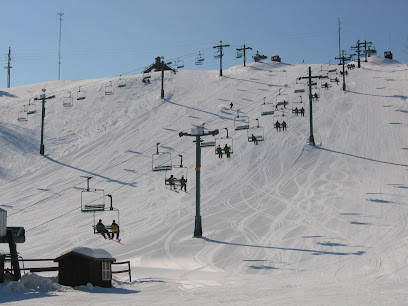 View of Mt Kato ski resort in Mankato, Minnesota featuring a ski lift amidst a bustling winter sports scene, with a chalet visible in the distance.
