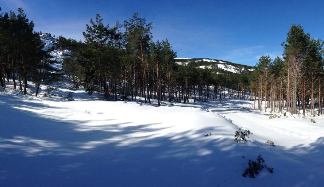 Winter sports enthusiasts enjoying the stunning snowy landscape of Manzaneda in Ourense, Spain. A chalet and winter sports centre dot the picturesque scene.