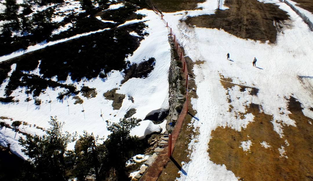 A bustling winter sports scene at Manzaneda in Ourense, Spain, featuring a picturesque chalet, a functioning ski lift, and a skier enjoying the stunning winter landscape.