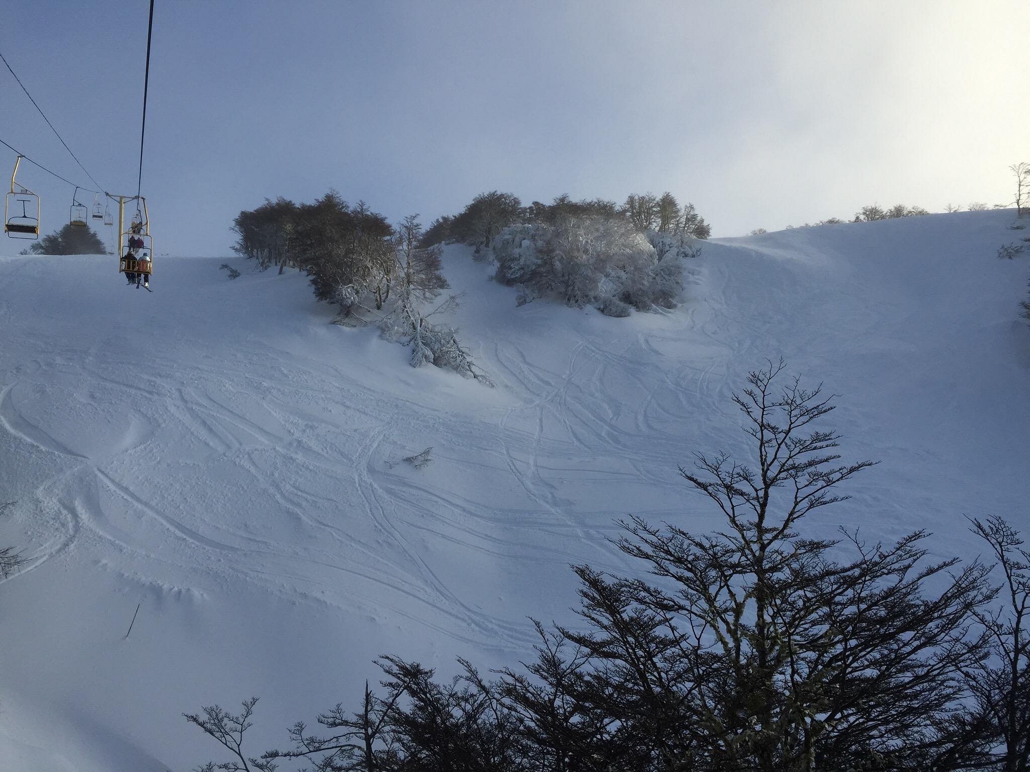 A chilly winter scene at Club Andino in Chile featuring a ski lift and chalet with skiers enjoying the snow-covered slopes.