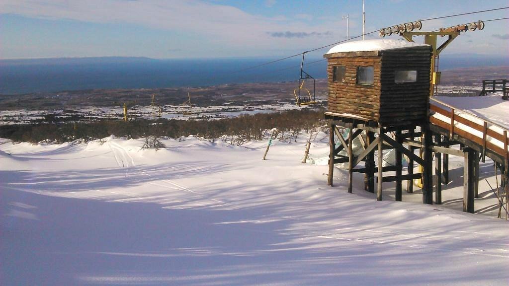 A picturesque winter scene at Club Andino in Chile, featuring a charming chalet surrounded by snowy landscapes and a ski lift, depicting a vibrant winter sports environment.