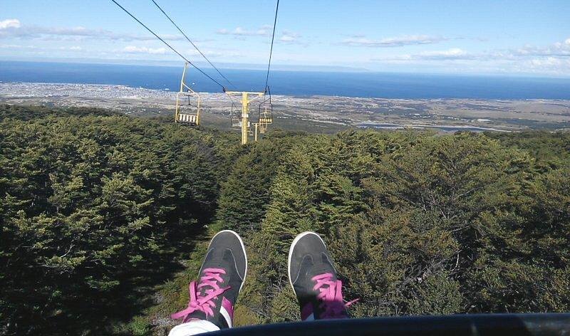 A picturesque view of Club Andino in Punta Arenas Chile featuring a charming chalet and a ski lift against the backdrop of a mountain. The scene is set on a sunny day with a mountain bike nearby.