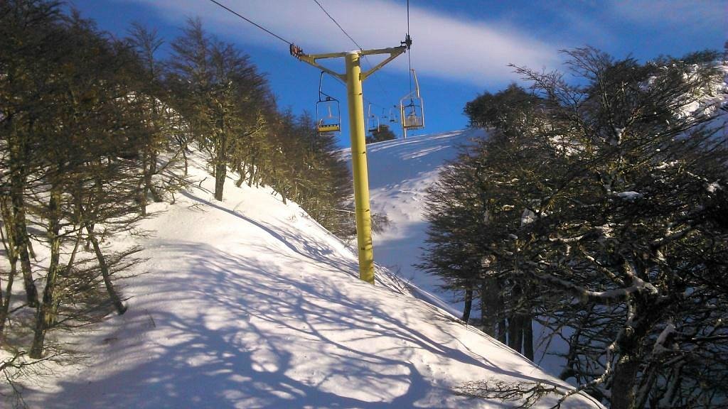 View of the scenic Club Andino in Chile showcasing a charming chalet, a ski lift in the distance, amidst a beautiful winter landscape offering winter sports activities.