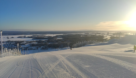 A skier enjoying a winter sports scene at Tahko ski resort in Kuopio, East Finland, surrounded by stunning winter scenery with a charming challet in the background.