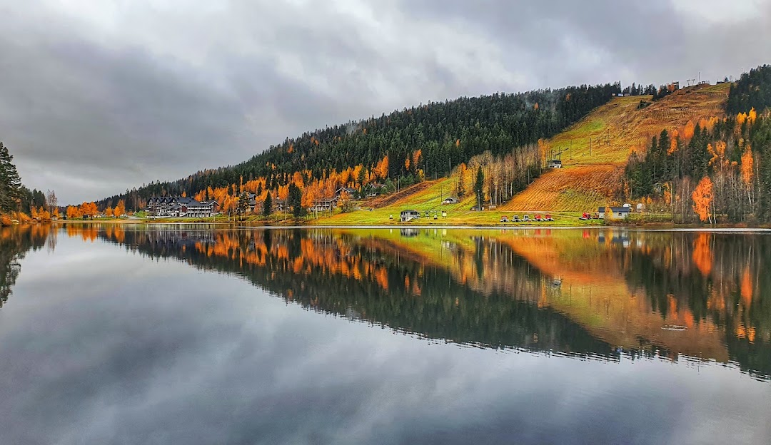 A serene view of a lake in Tahko, Northern Savonia, Finland. A charming ski resort, challet, and lodge add a cozy feel to the snowy winter sports scene.