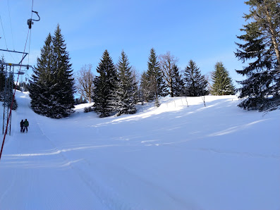 A vivid winter sports scene at Axalp Tschingellift in Bernese Oberland, Switzerland, featuring stunning winter scenery with a charming chalet and a bustling winter sports center.