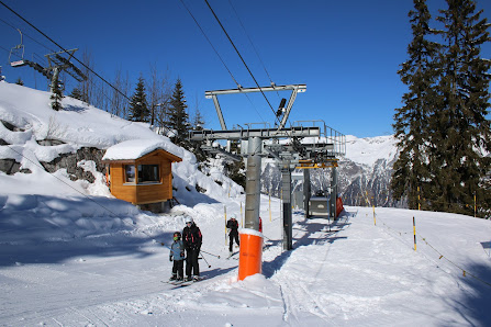 View of the Axalp Tschingellift, a ski lift at a resort in Bernese Oberland, Switzerland. A skier is visible in the distance amidst a wintery landscape, creating a classic winter sports scene.