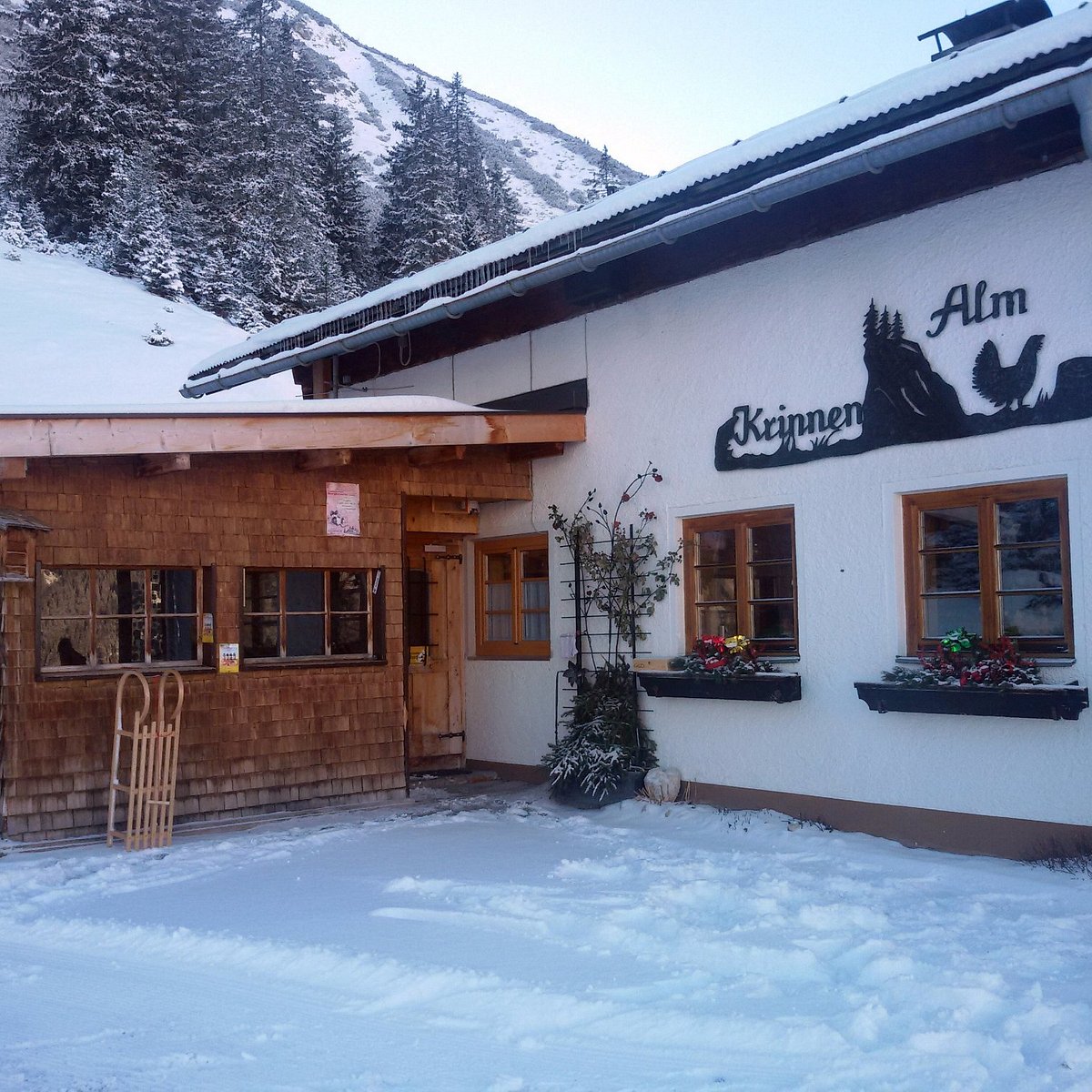 Krinnenalpe in Austria - a restaurant in the snow with mountains in the background.