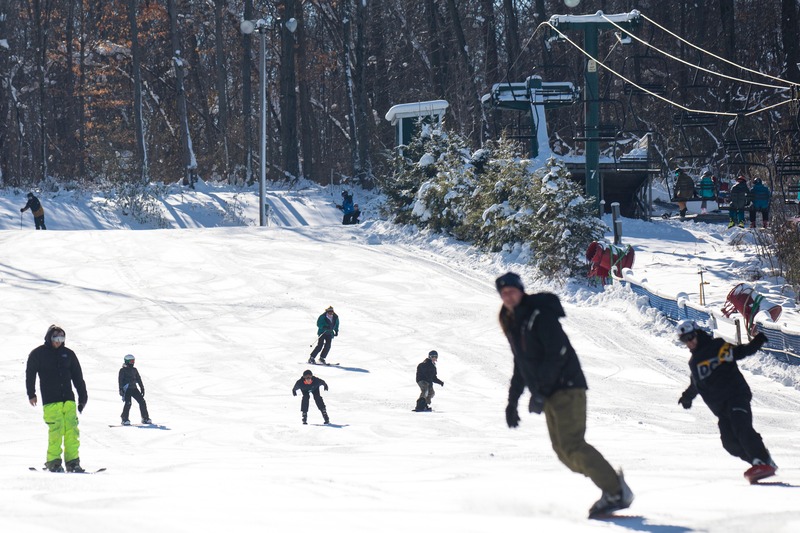Winter scene at Bittersweet in Otsego, Michigan, featuring active skiers dotting the snow-covered slopes and enjoying winter sports activities.