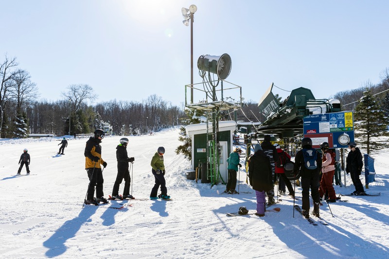 Winter sports enthusiasts enjoying a day at the Bittersweet ski resort in Otsego, Michigan, USA. The ski lift and stunning winter scenery enhance the lively atmosphere of this popular skiing destination.