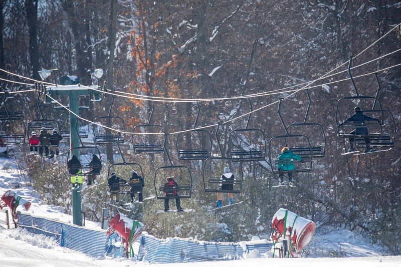 A winter sports scene at Bittersweet in Otsego Michigan showcasing a ski lift skiers and overall ambiance of a ski resort.