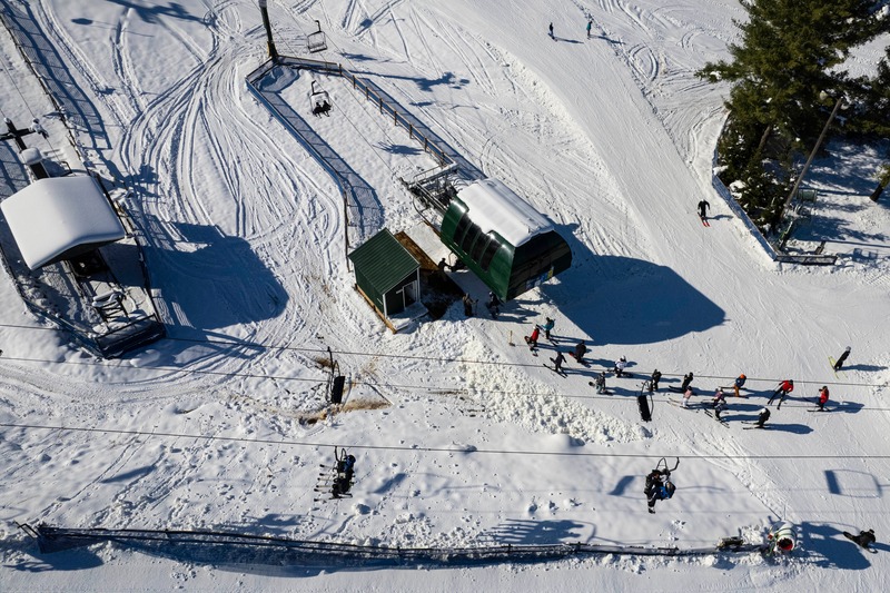 View of Bittersweet ski resort in Otsego Michigan showcasing a bustling winter sports scene. Visible are a ski lift transporting eager skiers up the snow-dusted slopes