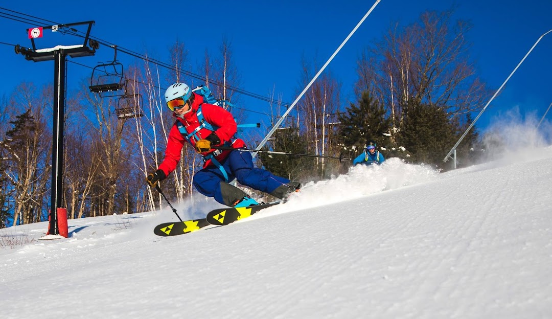 A snowboarder skillfully descending the snowy slopes of Black Mountain in Jackson New Hampshire. The pristine white snow under a clear blue sky provides a perfect setting for winter sports.
