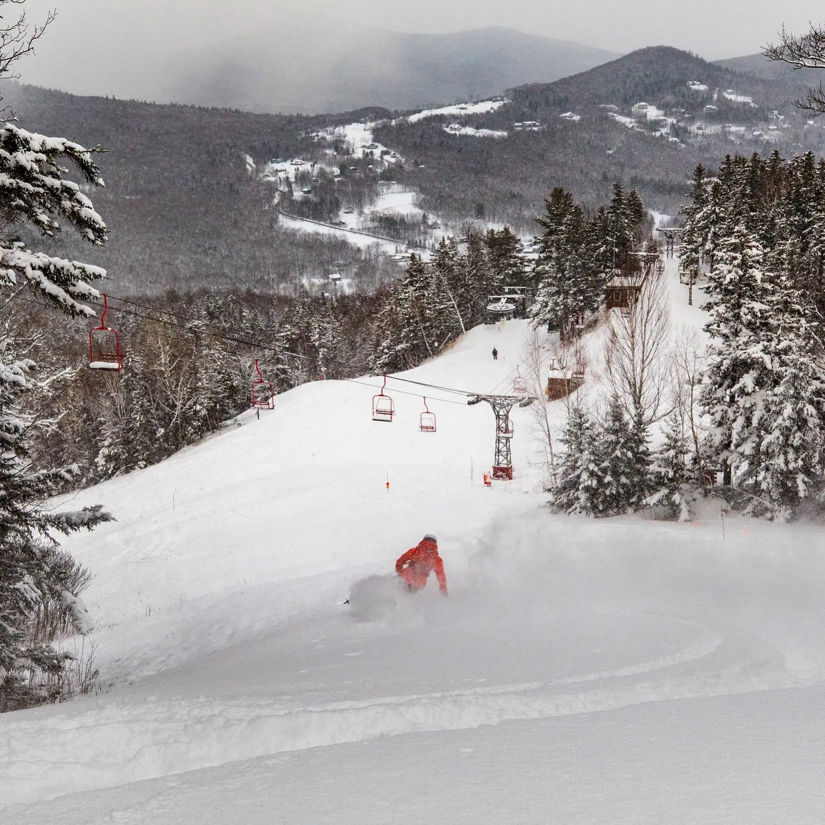 A thrilling winter sports scene at Black Mountain ski resort in Jackson New Hampshire USA. Skiers make their way down snow-covered trails with a snowmobile visible in the distance.