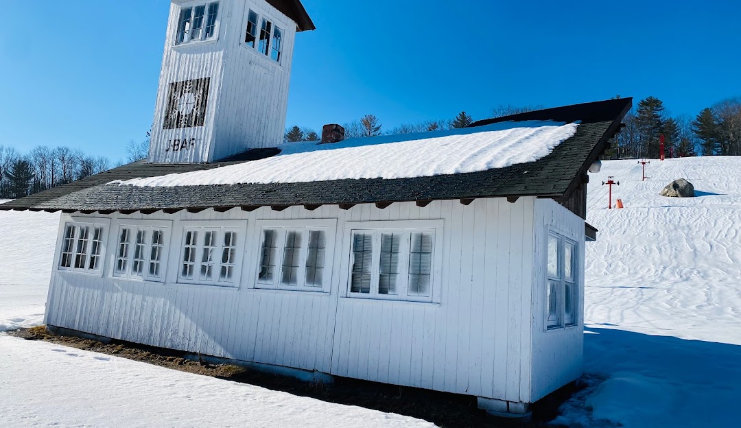 View of Black Mountain in Jackson, New Hampshire, highlighting a winter sports centre. A charming challet and rustic mountain hut can also be seen, providing a picturesque winter sports scene.
