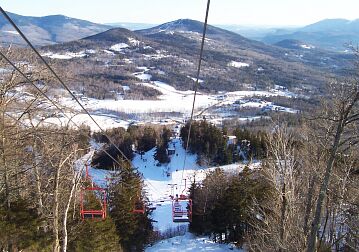 View from Black Mountain in New Hampshire featuring a ski lift ski resort and a skier speeding down the snow-covered slopes