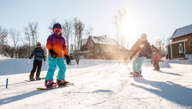 A family enjoying a day of winter sports at Asessippi Ski Resort in Inglis, Manitoba, Canada, with a child learning to ski.