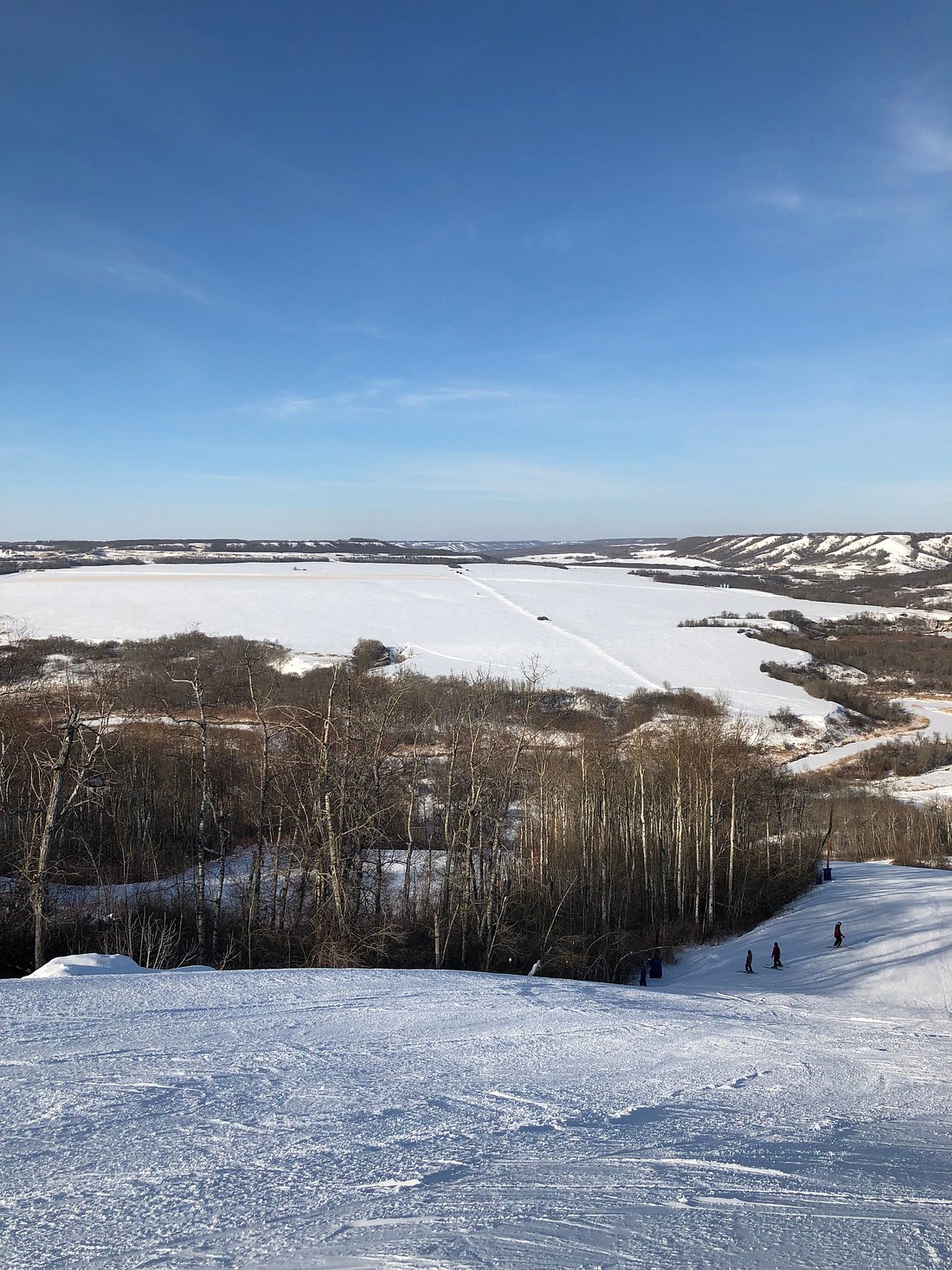 Winter sports enthusiasts enjoying a day at Asessippi ski resort in Inglis, Manitoba with a scenic view of the challet amidst the picturesque snow-covered Canadian landscape.