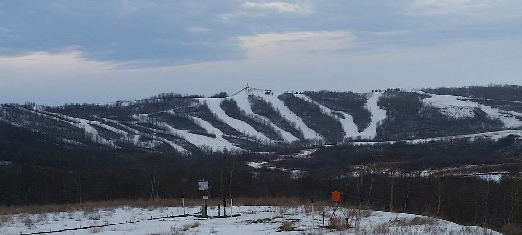 A scenic winter view of Asessippi Ski Resort in Inglis Manitoba Canada displaying snow-capped slopes a looming mountain in the backdrop and a visible ski lift.