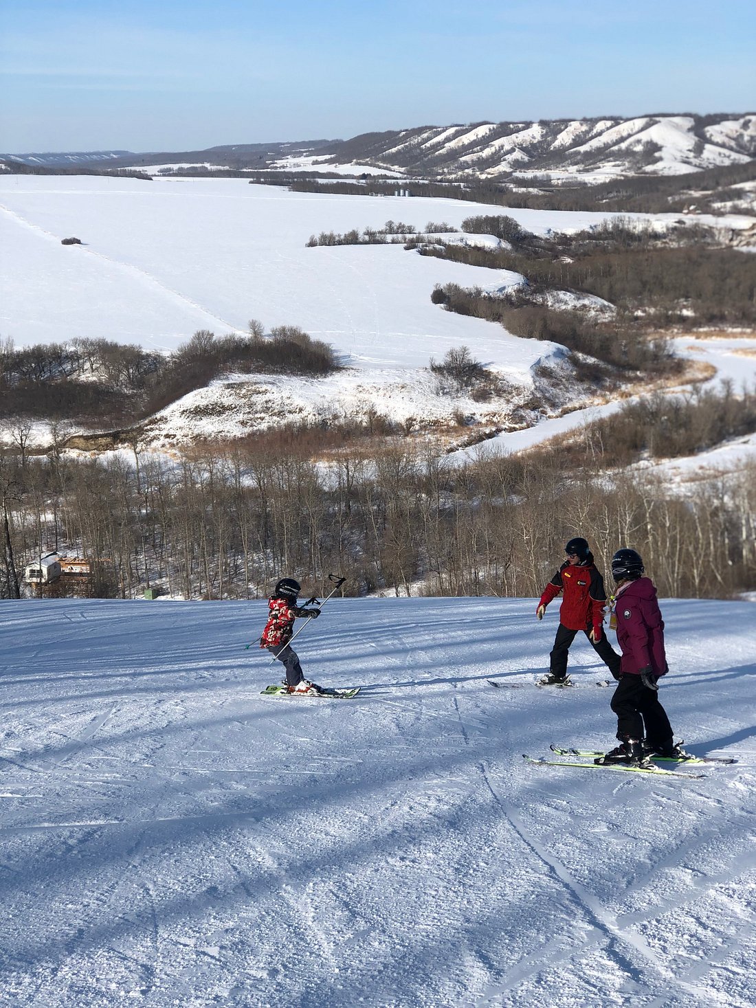Winter scene at Asessippi ski resort in Inglis, Manitoba, Canada, featuring a family and group of people enjoying a day of skiing.