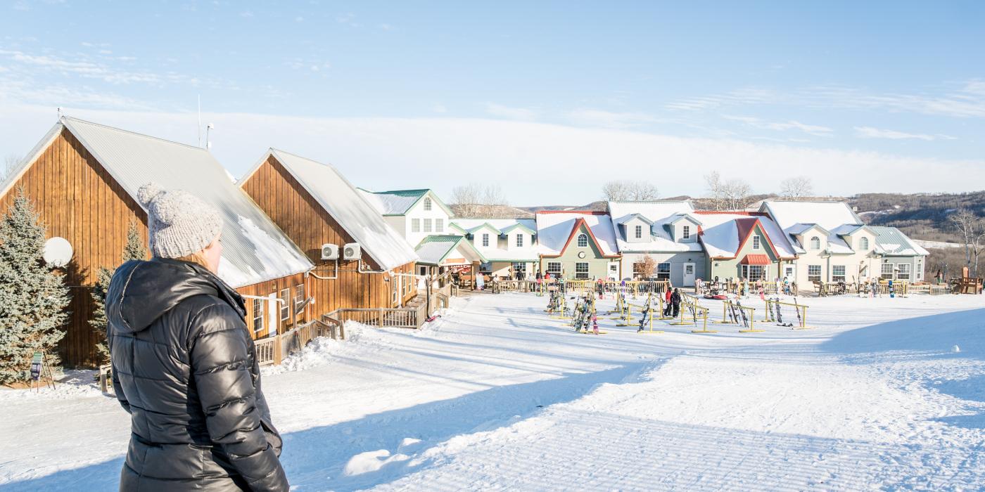 Asessippi in Canada - a man standing in the snow in front of a row of houses.