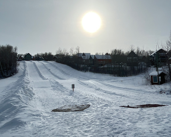 Winter sports scene at Asessippi in Inglis, Manitoba, Canada featuring a bustling winter sports centre, a charming chalet, and adventurous skiers gliding at the vibrant ski resort.