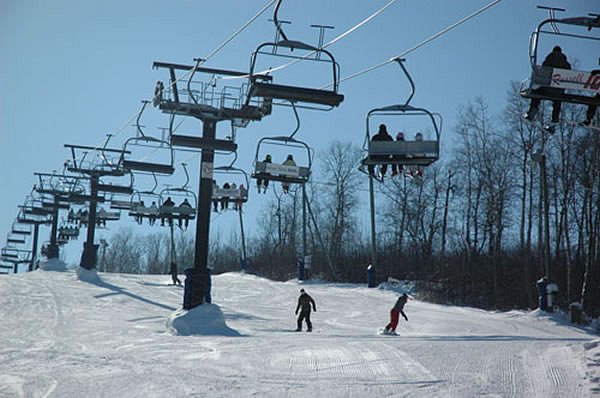 A scenic winter sports scene at Asessippi in Inglis Manitoba featuring a ski lift and a chalet amidst a bustling ski resort providing a picturesque view of the Canadian landscape.