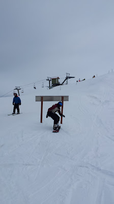 A skier enjoying a brisk run down the slope at Asessippi ski resort in Inglis, Manitoba, Canada with a chalet and ski lift visible in the background.