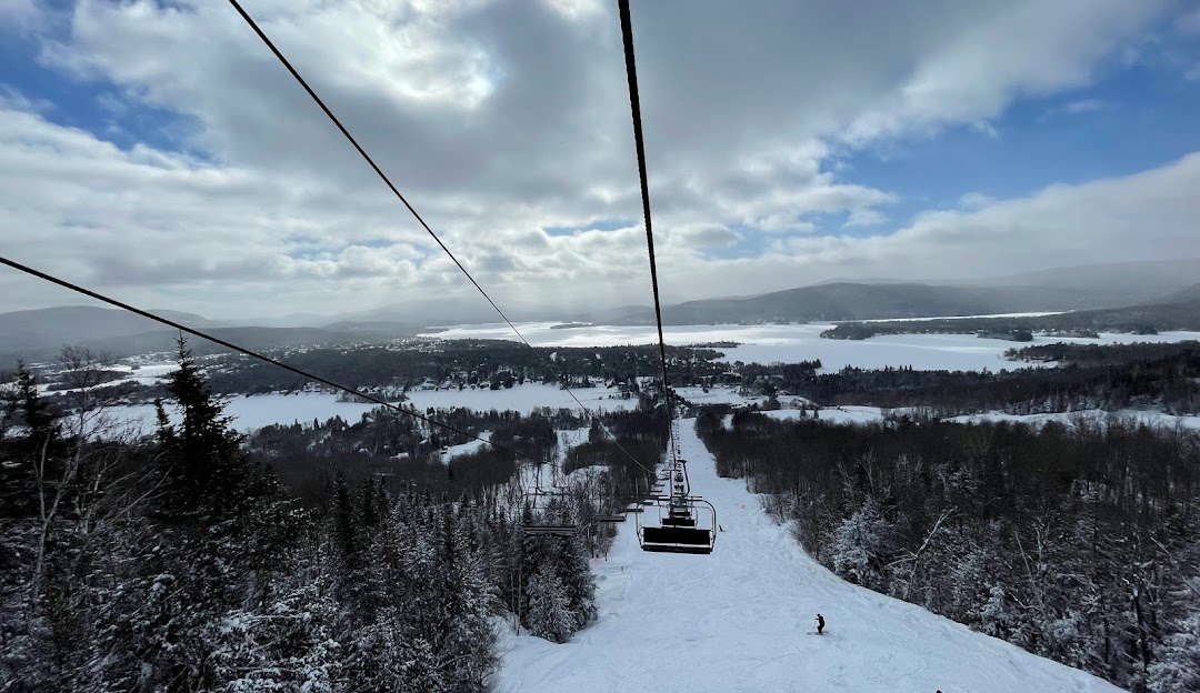View of Ski Garceau in Lanaudière, Canada showing a ski lift in operation. A skier can be seen on the slopes amidst a stunning winter scene, embodying the thrill of winter sports.