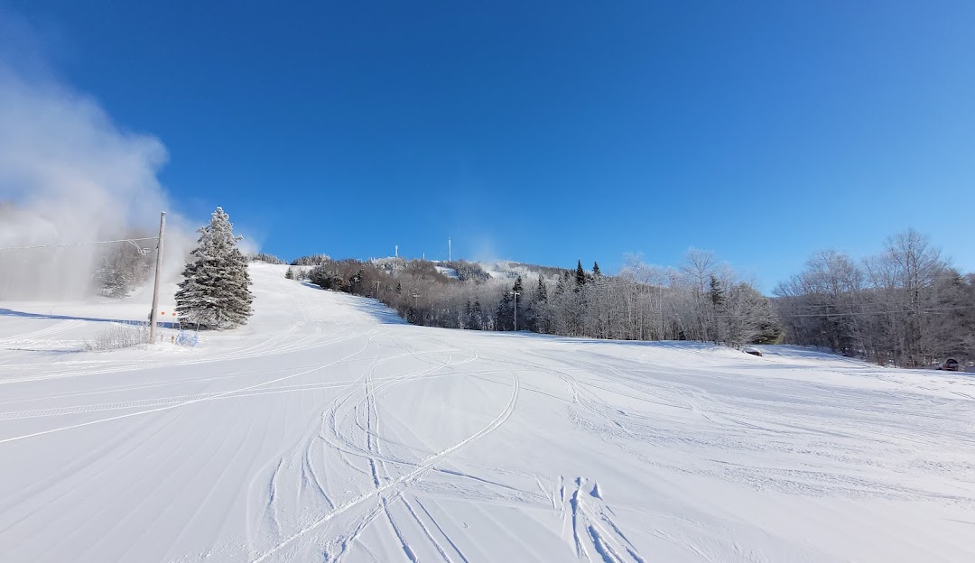 Winter scene at Ski Garceau in Quebec, Canada, showcasing a bustling ski resort amid stunning winter scenery complete with a charming chalet.