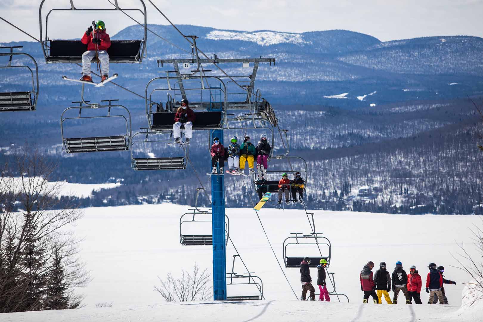 Skiing scene at Ski Garceau in Quebec Canada featuring a ski lift and resort. A group of people can be seen skiing down the snowy slopes on this crisp winter day.