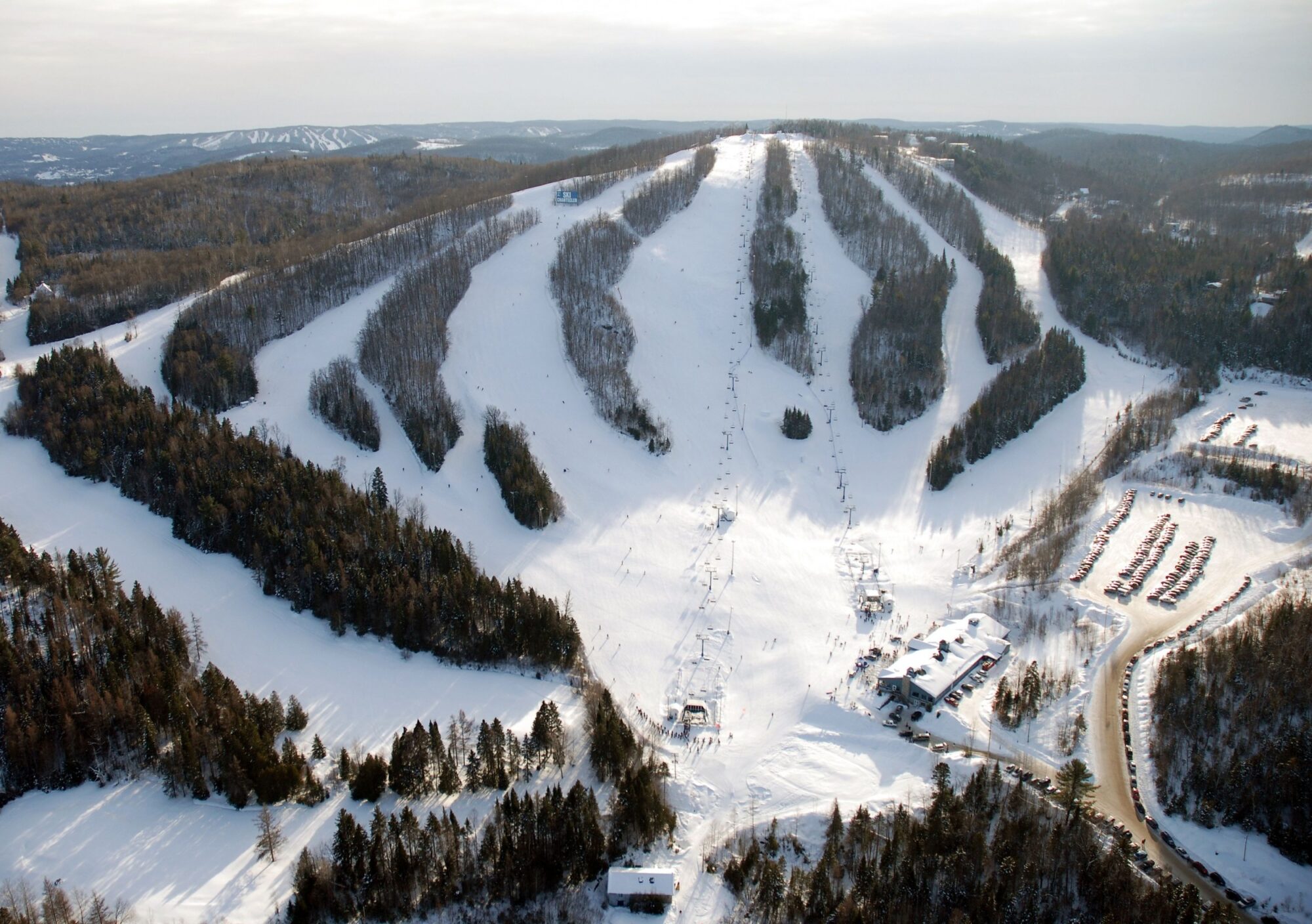 A picturesque view of Ski Chantecler resort in Quebec Canada. Features snow-covered slopes ski lifts and skiers enjoying winter sports in a bustling winter sports centre.