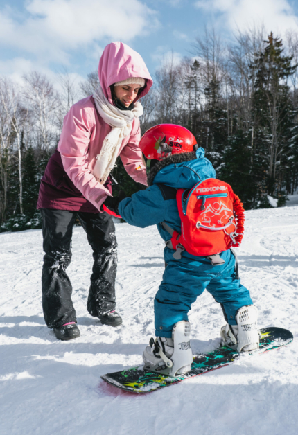 A snowboarder carving down the slopes at Ski Chantecler in Sainte-Adèle Quebec Canada. The weather is clear showing the stunning snowy landscape that surrounds the resort.