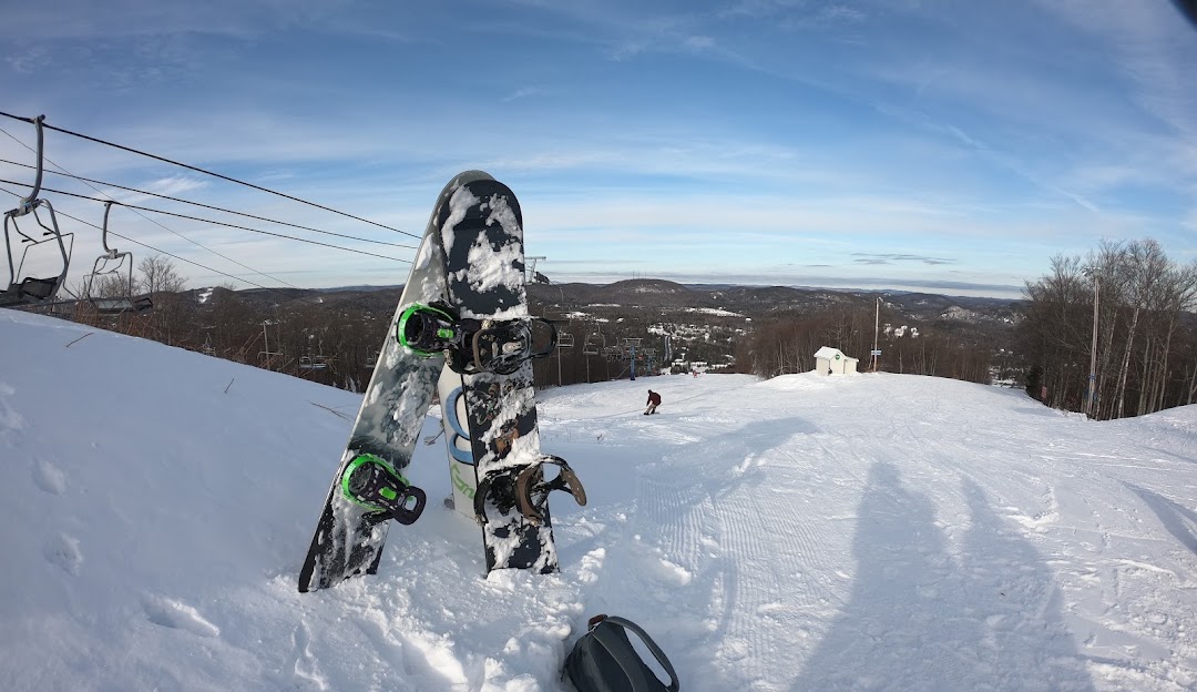 A snowboarder taking on the pristine slopes at Ski Chantecler in Laurentides Sainte-Adèle Quebec Canada. Snow capped trees line the route