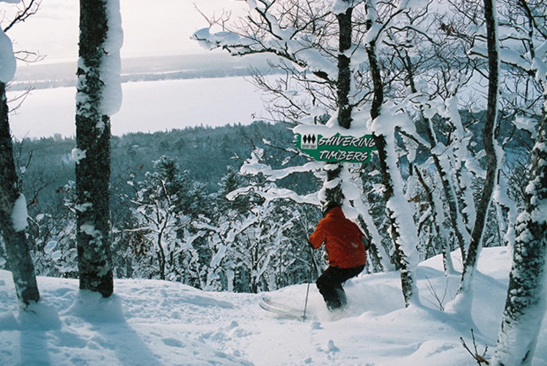A skier and snowboarder enjoying winter sports at Mt Bohemia in Mohawk, Michigan. The stunning winter scenery encompasses snow-covered trees and pristine slopes.