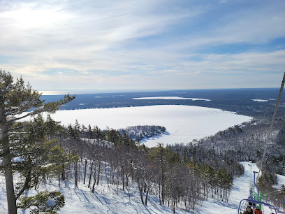 Winter sports enthusiasts enjoying the stunning snowy scenery of Mt Bohemia, Michigan. Snow-capped mountain landscape overlooks a tranquil lake on a clear winter day.
