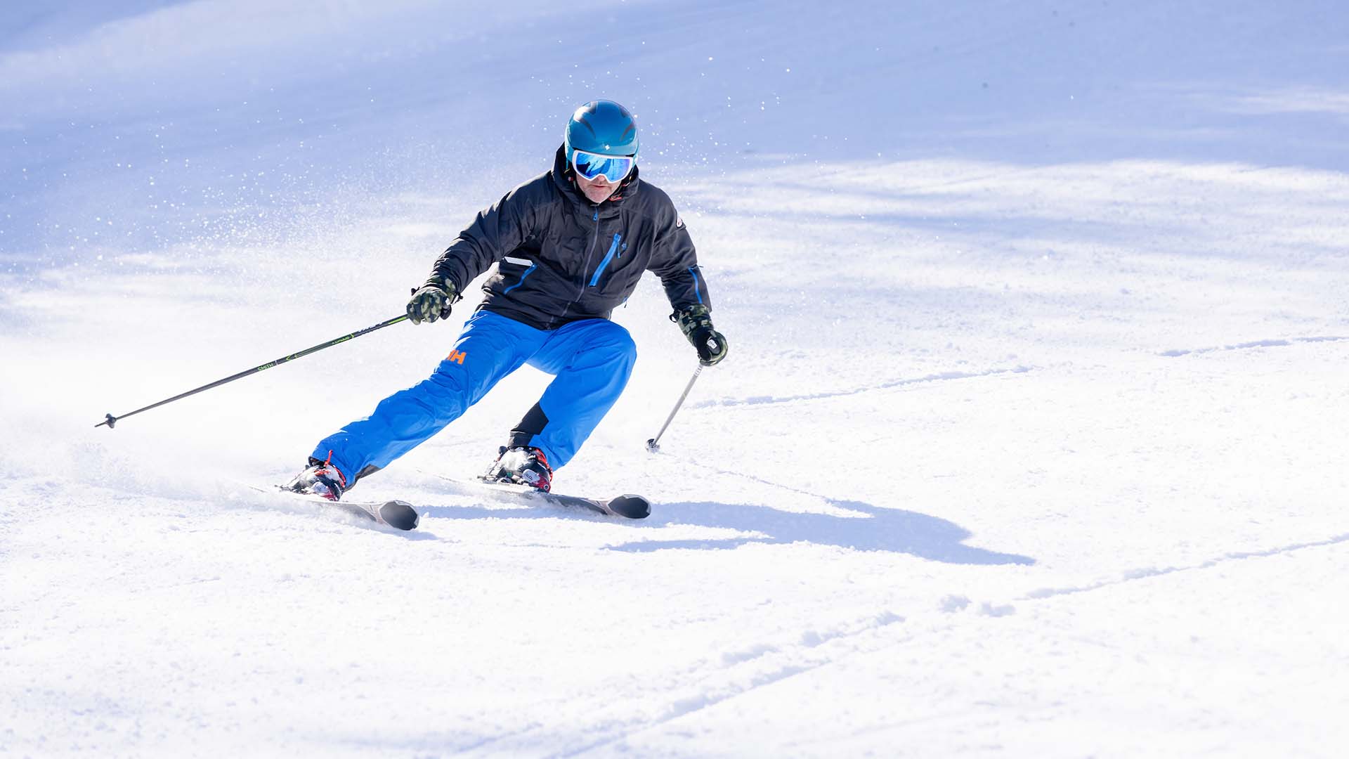 A skier smoothly glides down the snowy slopes of Ben Eoin, Nova Scotia, surrounded by stunning winter scenery. A hint of other winter sport activities can also be noted in the background.