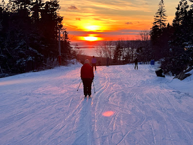 Winter sports scene at Ben Eoin, Nova Scotia, with a skier enjoying the slopes amidst a stunning winter scenery, including a quaint chalet in the distance.